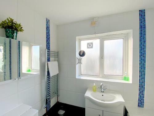 een witte badkamer met een wastafel en een raam bij 3 Bedroom flat in Hockley Birmingham near city centre, comfy and convenient in Birmingham