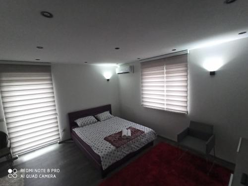 a bedroom with a bed and two windows with blinds at Apartmani Kula in Tuzla
