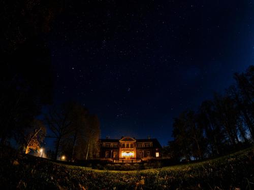 Une grande maison éclairée la nuit dans l'établissement Piena muiža - Berghof Hotel & SPA, à Sieksāte