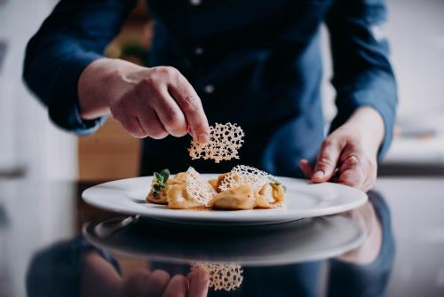 a person holding a plate of food on a table at Relais Castello di Razzano in Alfiano Natta