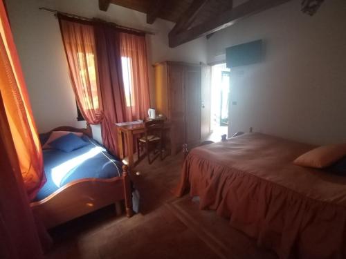 a bedroom with a bed and a desk and window at Agriturismo Le oche selvatiche in Lauzacco