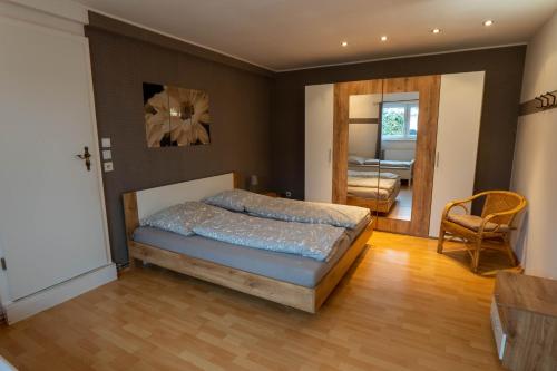 een slaapkamer met een bed, een stoel en een deur bij Harznester - Ferienhaus am Horstberg in Wernigerode