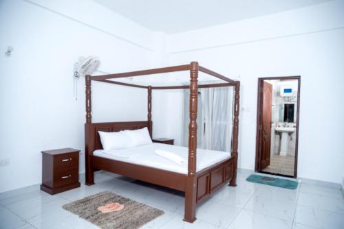 a bedroom with a canopy bed and a mirror at Precious Moments Suite in Mombasa