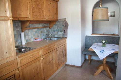 a kitchen with wooden cabinets and a sink and a table at Ferienwohnungen "Kober" in Hopfgarten im Brixental