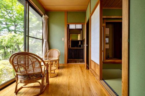 a room with a table and chairs and a window at 由布の里 旅荘 牧場の家 Ryoso Makibanoie in Yufuin
