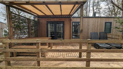 une grande terrasse en bois avec une table et des chaises en bois dans l'établissement Mobil-home Camping Biscarosse, à Biscarrosse