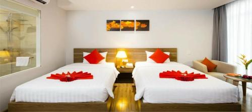 two beds in a hotel room with red bows on them at Maple Leaf Hotel & Apartment in Nha Trang