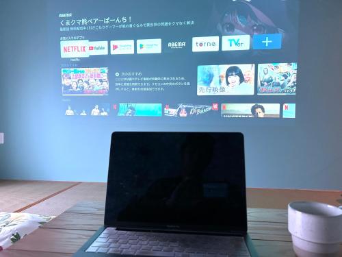 a laptop computer sitting on a table in front of a screen at SHARIN in Kanazawa