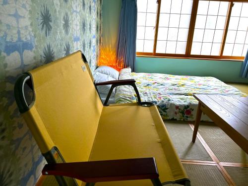 a yellow chair in a room with a bed and a table at SHARIN in Kanazawa