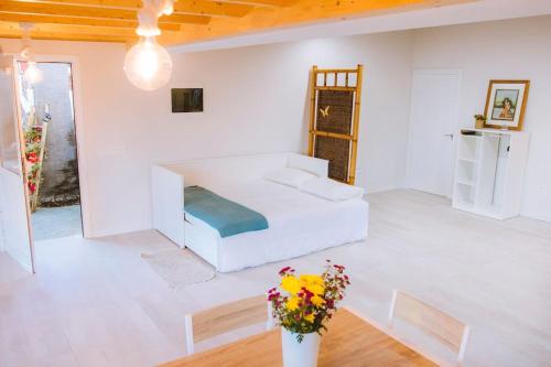ein weißes Zimmer mit einem Bett und einer Vase aus Blumen in der Unterkunft Casita Gopal in Icod de los Vinos