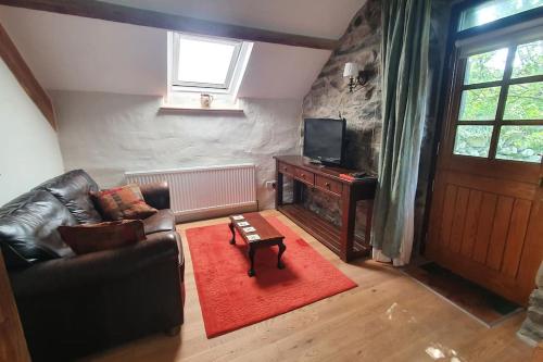 a living room with a leather couch and a television at The Hayloft Llwyndu in Barmouth