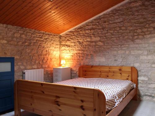 - une chambre avec un lit en bois dans un mur de briques dans l'établissement Maison Charme Ancien, Jardin, 2Km Centre St Pierre, 20min Plage - 5 Couchages - FR-1-246A-65, à Saint-Pierre-dʼOléron