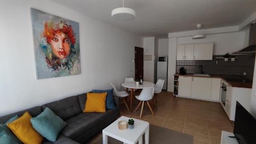 ein Wohnzimmer mit einem Sofa und einem Tisch sowie eine Küche in der Unterkunft Puipana Apartment, Fuerteventura in Puerto del Rosario