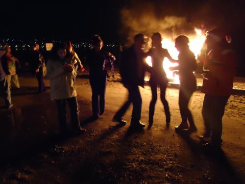 a group of people standing around a bonfire at night at Bells Motel in Seferihisar