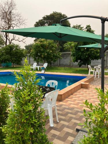 un patio con una sombrilla verde y sillas y una piscina en ANGEL RESORT i, en Amphoe Sawang Daen Din