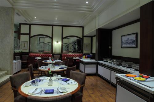 un comedor con mesas y sillas en un restaurante en Regency Hotel, en Bombay
