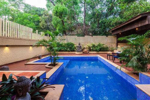 a swimming pool in a backyard with a fence and trees at StayVista's The Happy Hive - Cozy rooms and a pool for a delightful stay in Lonavala
