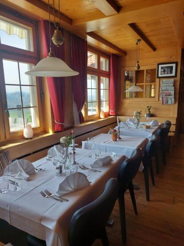a dining room with white tables and chairs and windows at Alpenblick Ferenberg Bern in Stettlen