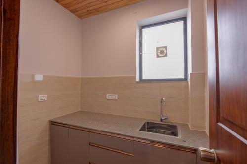 a kitchen with a sink and a window at Kailasham Stay in Dharamshala