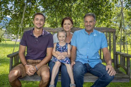 una familia está sentada en un banco del parque en Rutarhof en Rosegg