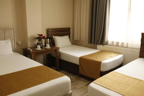 ein Hotelzimmer mit zwei Betten und einem Tisch mit Blumen in der Unterkunft Birlik Hotel in Istanbul