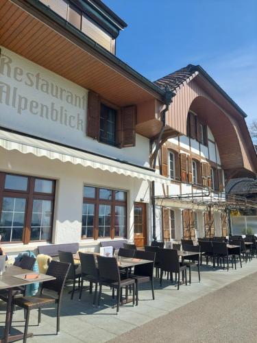 a restaurant with tables and chairs in front of a building at Alpenblick Ferenberg Bern in Stettlen