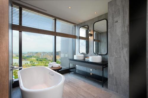 La salle de bains est pourvue d'une baignoire, de 2 lavabos et d'un miroir. dans l'établissement COZZI Blu, à Zhongli