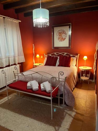 a bedroom with a bed with red walls and a chandelier at Chalet Robayera a línea de playa in Miengo