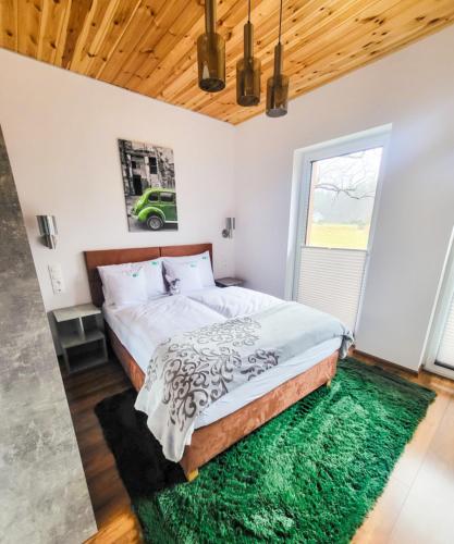 a bedroom with a large bed with a green rug at RIVER REST - ADULTS ONLY in Świeradów-Zdrój