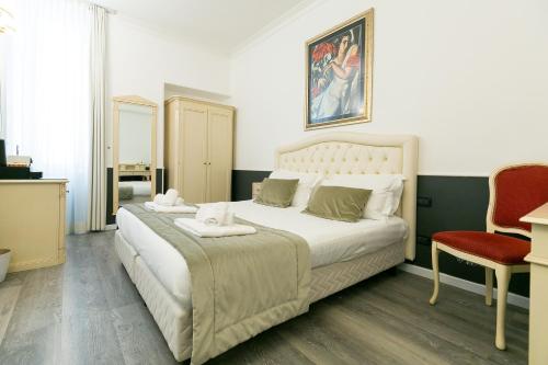 a bedroom with a large white bed and a red chair at Capitolium Rooms in Rome