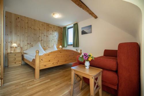 a bedroom with a bed and a couch and a table at Rutarhof in Rosegg