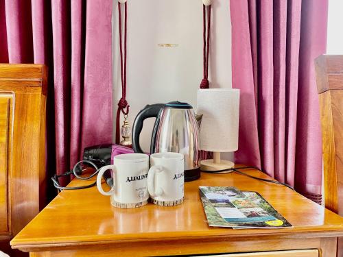 a table with a coffee pot and two mugs on it at Phong Nha - Tien's Cozy Homestay in Phong Nha