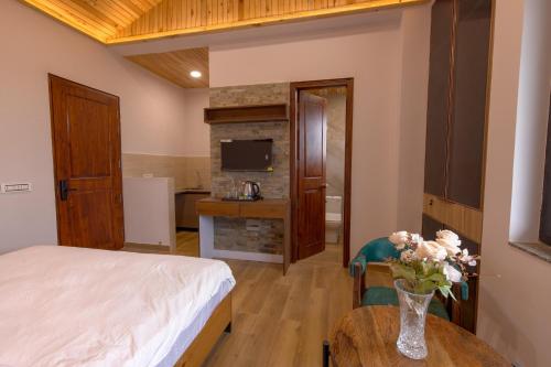 a bedroom with a bed and a table with a vase of flowers at Kailasham Stay in Dharamshala