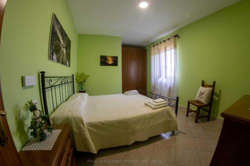 a green bedroom with a bed and a chair at La Cascina delle Viole in Norcia