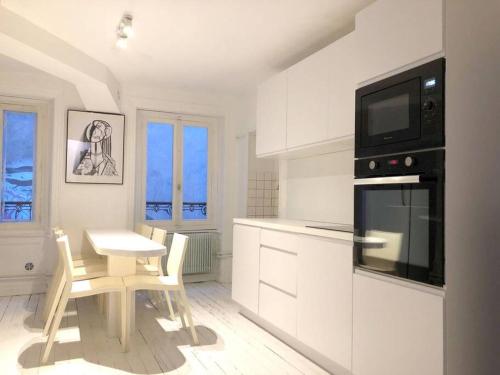 - une cuisine blanche avec une petite table et un four micro-ondes dans l'établissement Le gîte de la Cour des Arts, à Saint-Dié-des-Vosges