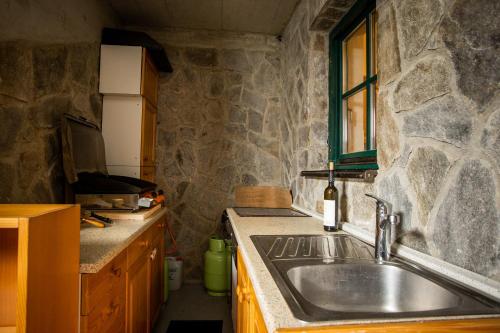 cocina con fregadero y pared de piedra en Martin Ski-In Apartment, en Hočko Pohorje