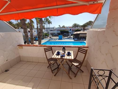 a table and chairs on a balcony with a swimming pool at Sunny terrace, fast WiFi relax & remote work quiet area in Arona