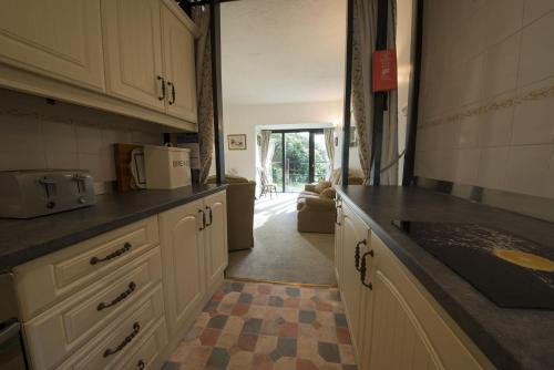 a kitchen with white cabinets and a checkered floor at Grange Cottage Lakeside Windermere in Newby Bridge
