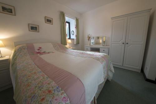 a bedroom with a bed with a floral bedspread at Grange Cottage Lakeside Windermere in Newby Bridge