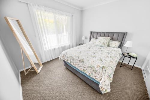 a white bedroom with a bed and a window at Cooma Luxe in Cooma