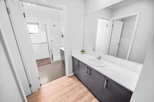 a white bathroom with a sink and a mirror at Cooma Luxe in Cooma