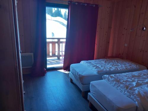 a bedroom with two beds and a large window at Appartement Le Pic in Samoëns