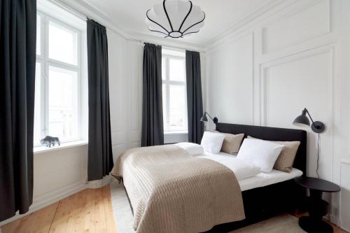 a white bedroom with a bed and two windows at Bright Apartment in the Old Town of Copenhagen in Copenhagen