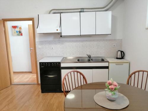 Il comprend une cuisine équipée d'une table, d'un évier et d'une cuisinière. dans l'établissement Apartman Anamarija, à Split