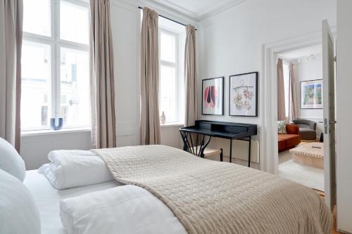 a white bedroom with a bed and a piano at Bright Apartment in the Old Town of Copenhagen in Copenhagen