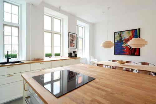 a kitchen with white cabinets and a wooden table at Bright Apartment in the Old Town of Copenhagen in Copenhagen