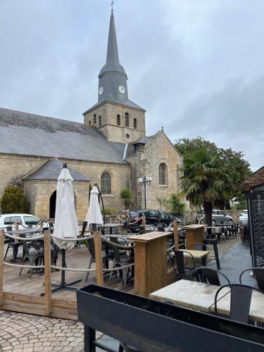 una iglesia con una torre de reloj, mesas y sillas en Hôtel Restaurant La Voile - Le Dock'er, en Locmariaquer