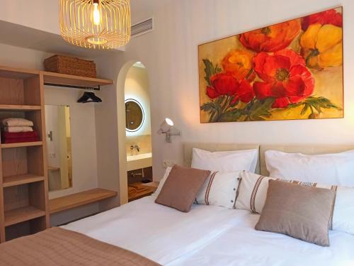ein Schlafzimmer mit einem weißen Bett und einem Gemälde an der Wand in der Unterkunft Luxe Haciënda La Campiña met verwarmd zwembad en tennisbaan. in Alhaurín el Grande