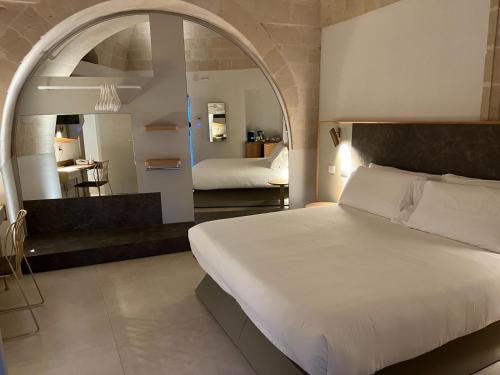 a bedroom with a large white bed and a bathroom at Euvodia Luxury Rooms in Matera
