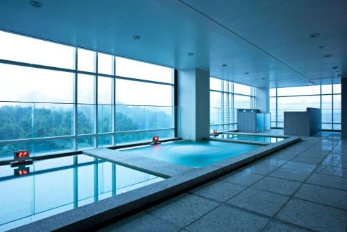 a large swimming pool in a building with windows at Ramada Plaza by Wyndham Suwon in Suwon